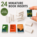 24 miniature book inserts shown on a white background, including stacks of blank white book covers and a few sample books with printed covers. A hand with teal nail polish holds one miniature book titled 'Held' by Anne Michaels.