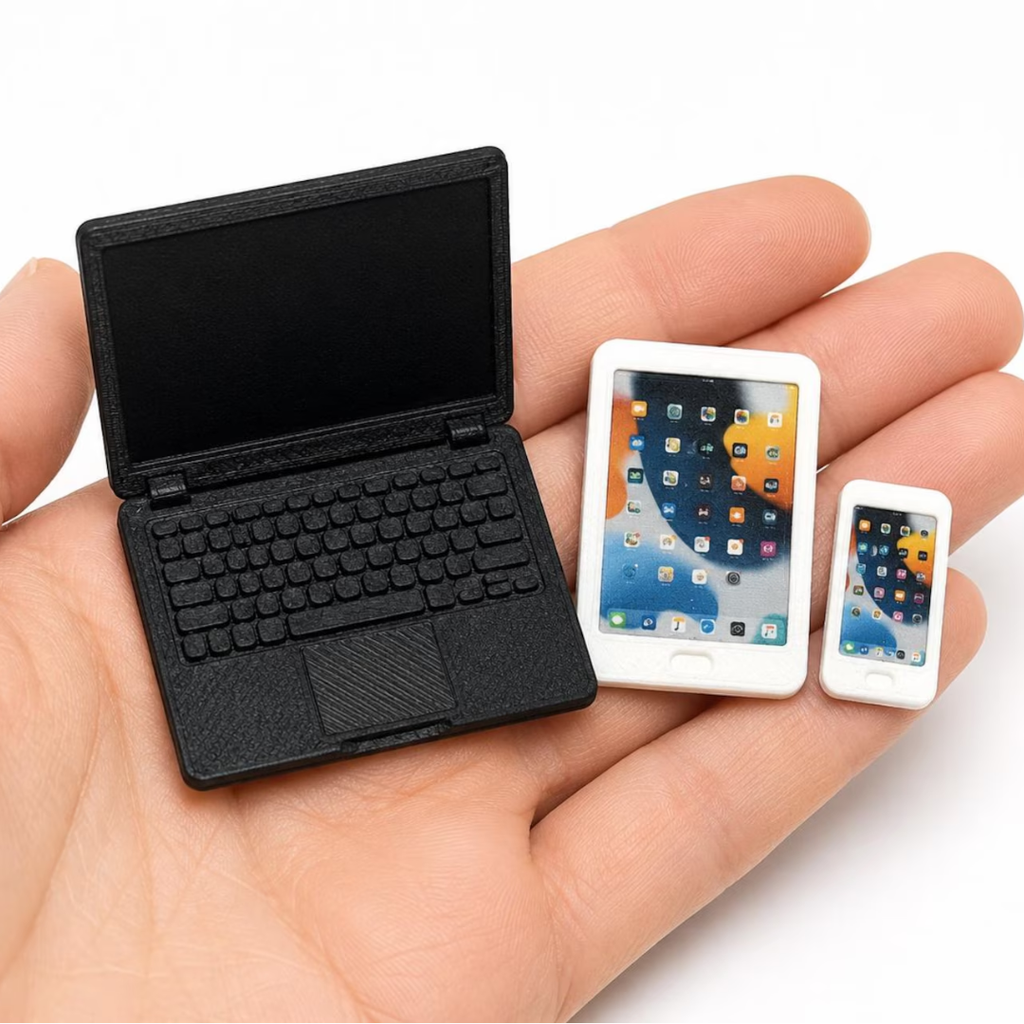 Miniature laptop, tablet and phone held in a hand to show scale