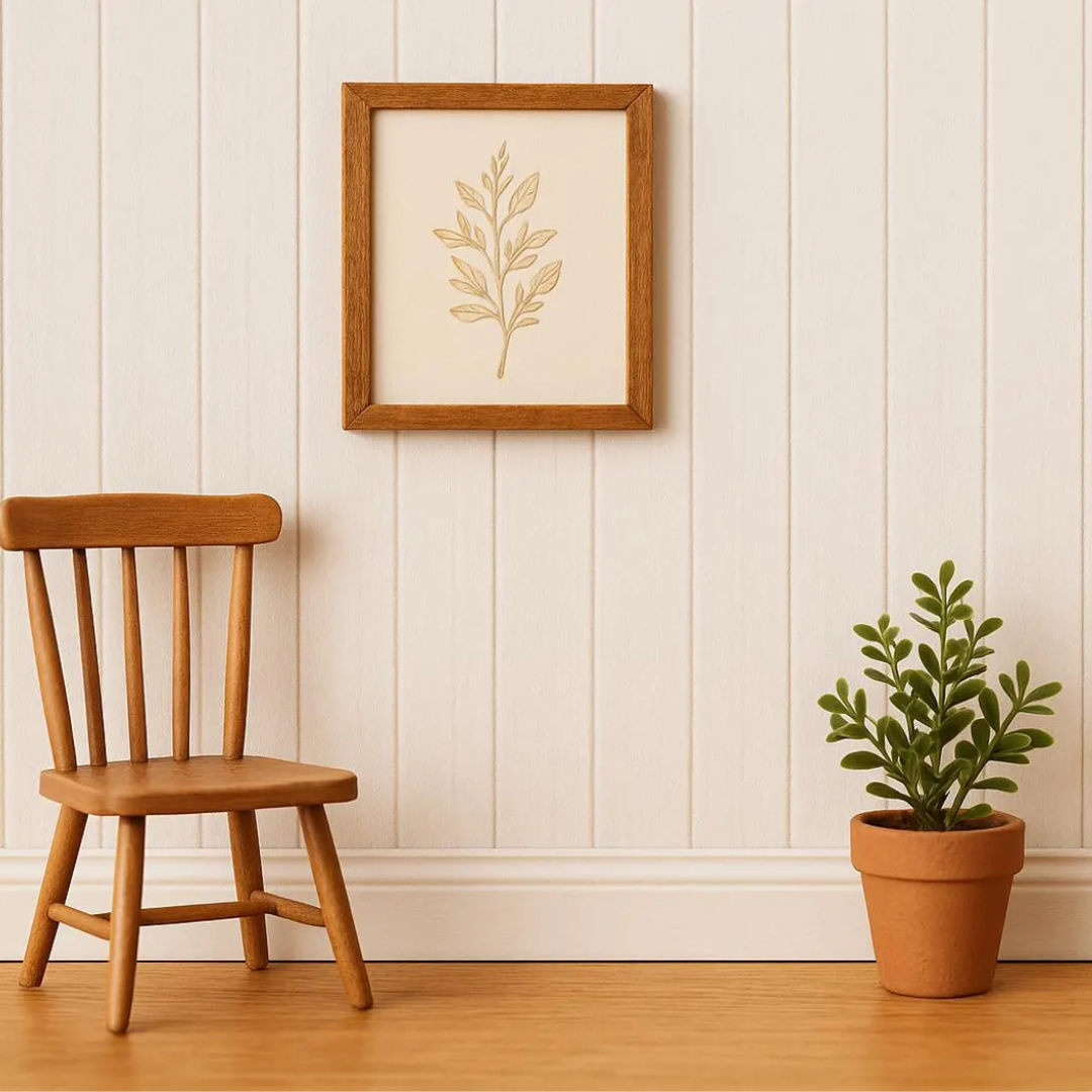 A framed botanical art print hangs on a white paneled wall above a wooden chair, with a potted green plant on the floor to the right.